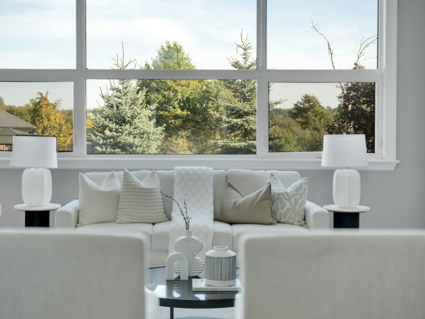 A bright living room with a wide window looking out onto trees.