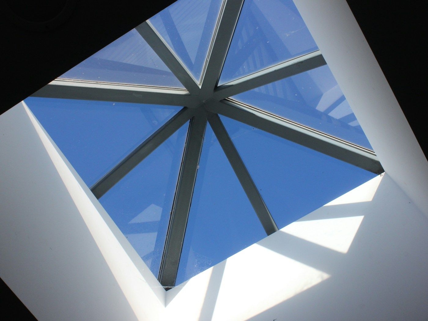 A roof lantern seen from inside a room, its glass panes framing blue sky.