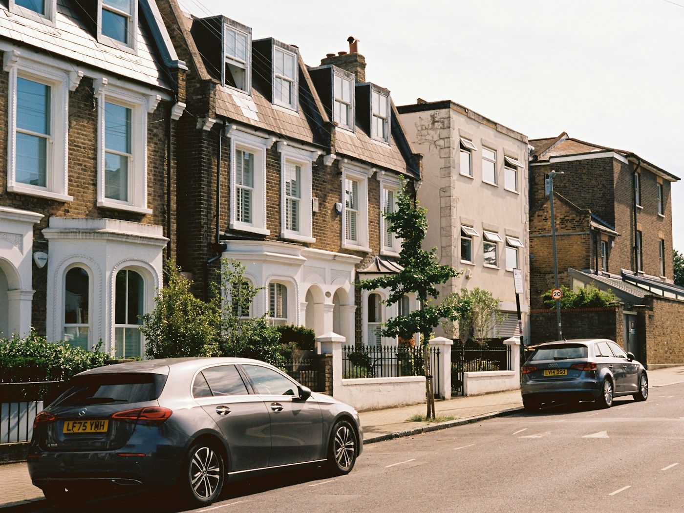 A row of terraced houses with bay windows along a quiet residential street.